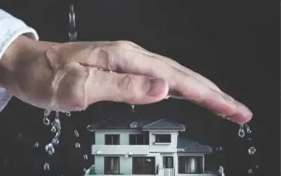 Hand die een huis beschermt tegen waterbeschadiging